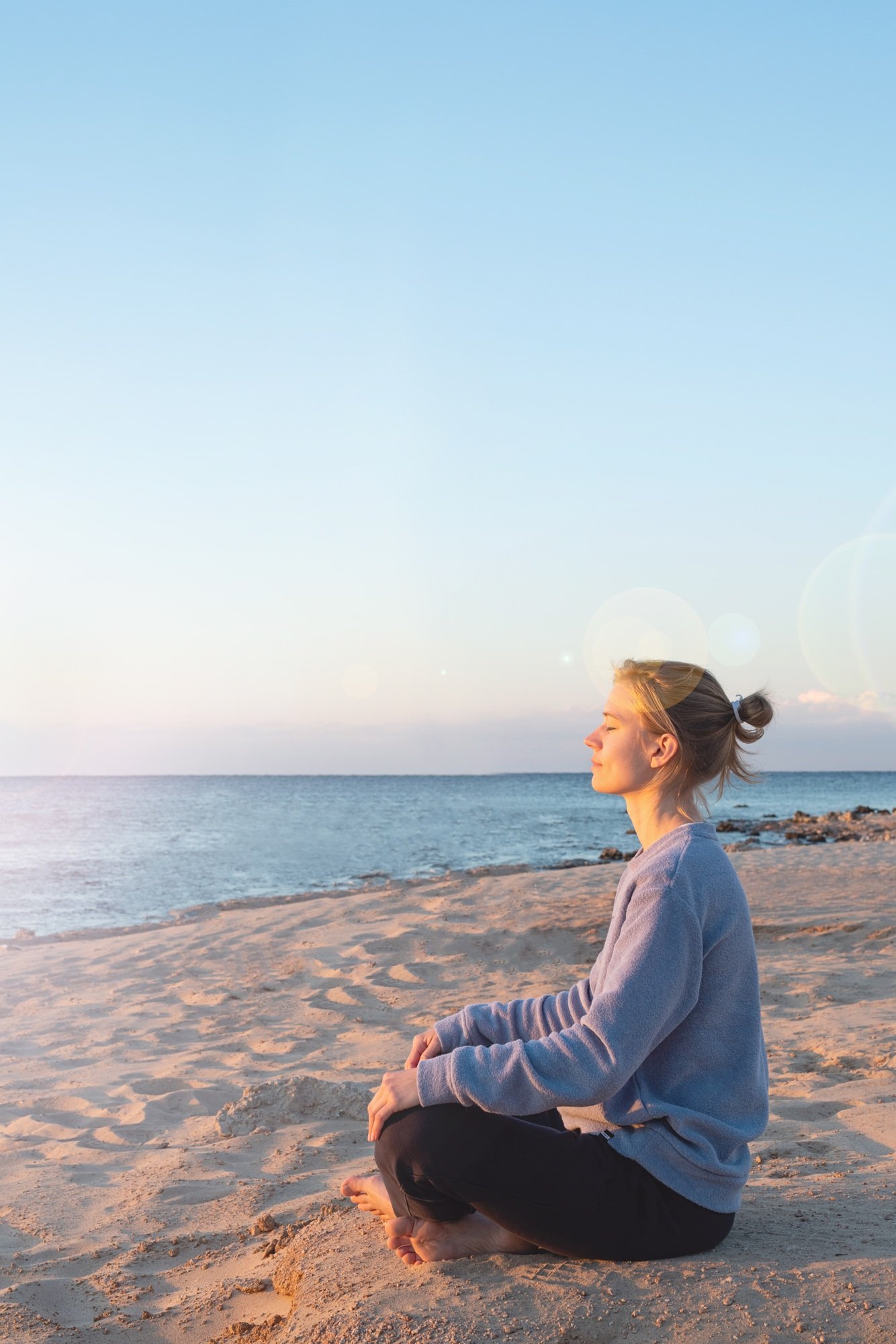 Young healthy woman practicing yoga on the beach at sunrise