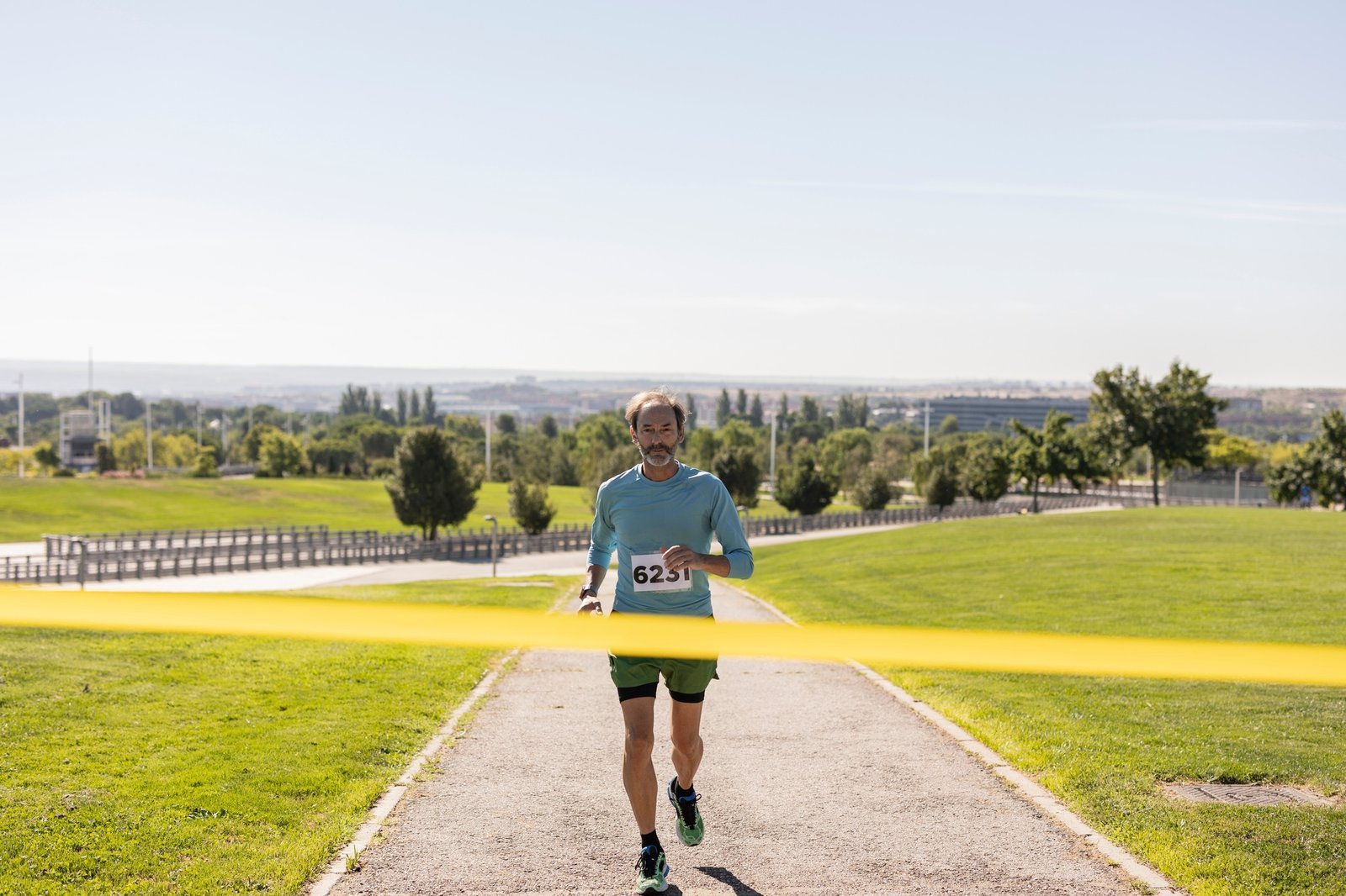 Senior male athlete crossing finish line in city park marathon race